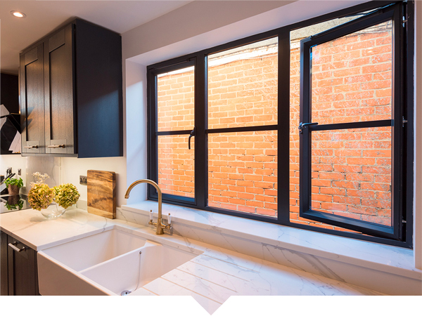 A modern black aluminium tilt-and-turn window installed in a kitchen, providing easy ventilation and a sleek design.